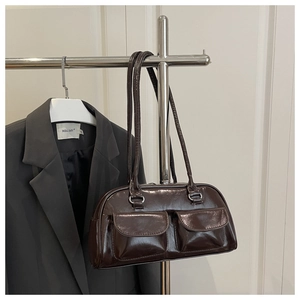 Detail of dark brown polished leather shoulder bag with two front flap pockets