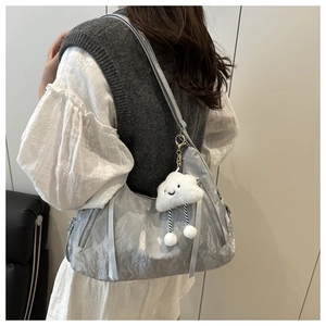 Silver metallic pleated tote bag with white plush cloud pendant worn over the shoulder