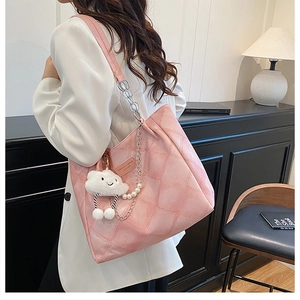Detail of pink quilted tote bag with pearl chain strap and plush cloud charm
