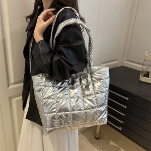 Silver quilted tote bag with metallic finish shown on model for a trendy modern style
