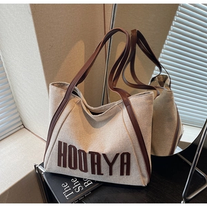 Detail of canvas tote bag with HOORYA embroidery and premium brown leather handle