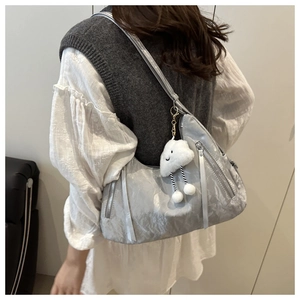 Detail of silver metallic shoulder bag with multiple zippers and a plush cloud charm