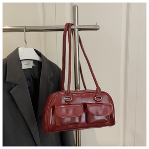 Detail of dark red glossy leather shoulder bag with two front pockets and long strap