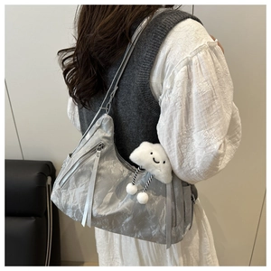 Silver metallic pleated backpack with multiple zippers and cloud plush charm on model