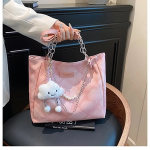 Detail of pink quilted tote bag featuring chain handles and a cute cloud plush pendant