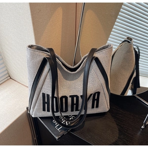 Detailed texture of high-capacity canvas tote bag with HOORAYA print and leather straps
