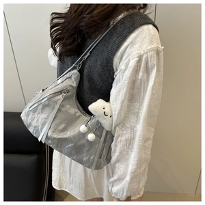 Detail view of silver hobo bag featuring wrinkled texture and white cloud plush charm