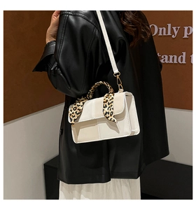 Close-up of a cream crossbody bag featuring leopard print scarf handle wrap detail
