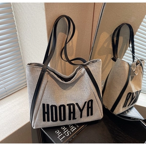Detail of the woven fabric texture and black leather trim on a large tote bag