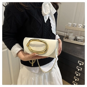 White leather clutch bag with large gold oval buckle and chain strap shown on model