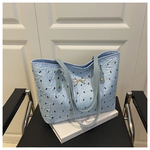 Detail of light blue tote bag with black bow prints and gold metal bow clasp hardware