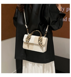 Detail of a chic handbag featuring leopard silk scarf and gold-tone hardware