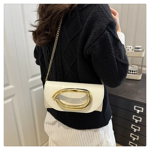 Close-up of white leather crossbody bag featuring a large oval gold metal buckle and chain