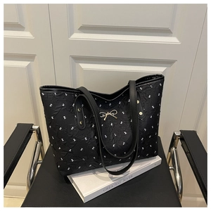 Detail of black tote bag featuring white bow prints and golden bow metal buckle