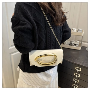 White leather shoulder bag with gold chain and large metal buckle detail on a model