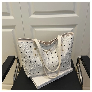 Detail of white tote bag featuring bubble texture fabric and black bow embroidery