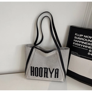 Detail of the minimalist HOORYA tote bag with black straps and bold letter print