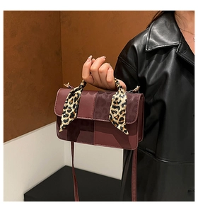 Detail of burgundy patchwork leather bag featuring a leopard print scarf-wrapped handle