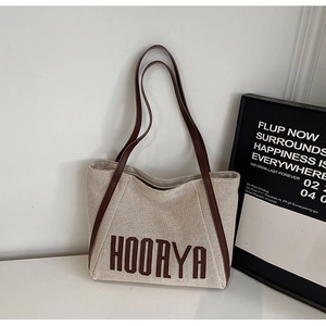 Detail of canvas tote bag with brown leather straps and HOORYA logo print