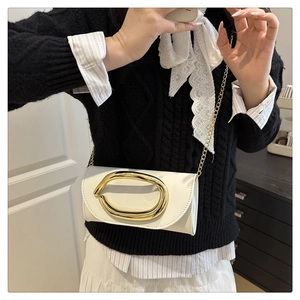 Close-up of a white mini crossbody bag with a large gold oval buckle and chain strap