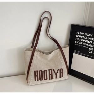 Detail of minimalist canvas tote bag with brown leather straps and HOORYA logo print