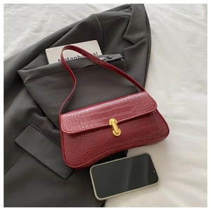 Detail of red crocodile pattern baguette bag with golden buckle on a grey suit