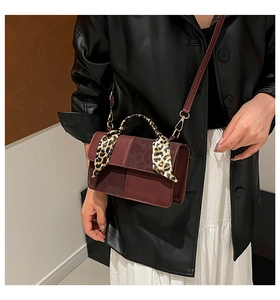 Detail of burgundy leather handbag featuring a leopard print scarf wrapped handle