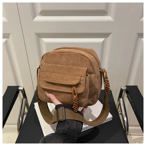Detailed close-up of corduroy shoulder bag with textured front pocket and woven drawstring