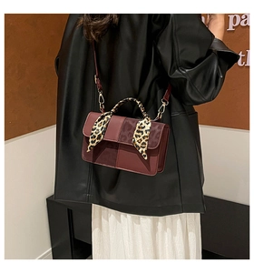 Close-up of a burgundy rectangular handbag featuring a leopard print scarf on the handle