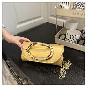 Detail of champagne gold satin evening bag with a large oval metal handle and chain strap