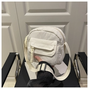 Close-up of white corduroy small crossbody bag with woven zipper pull and fabric strap