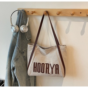 Detail of canvas tote bag with brown leather straps and HOORYA letter print