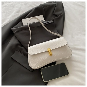 Detail of white crocodile embossed bag featuring a golden U-shaped buckle and fine texture