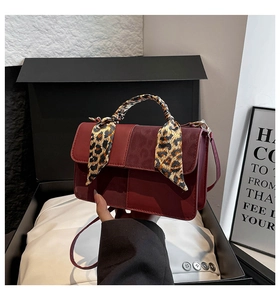 Detail of burgundy crossbody bag with leopard scarf and contrasting textures