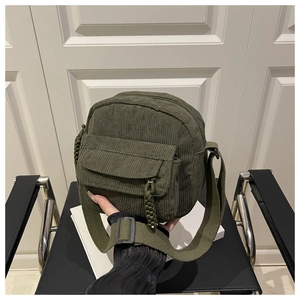 Detail of dark green corduroy crossbody bag showing ribbed texture and zipper pocket