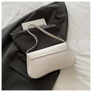 Detail of white crocodile embossed baguette bag on grey suit with minimalist aesthetic