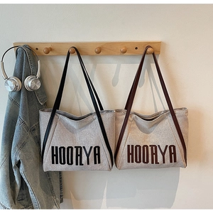 Detail of minimalist canvas tote bags with HOORYA lettering and slim leather straps