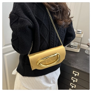 Detail of ginger yellow evening bag with gold U-shaped metal handle and chain