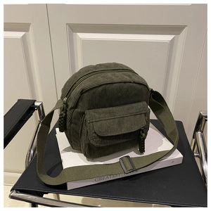 Close-up of military green corduroy crossbody bag with woven zipper and round main pocket