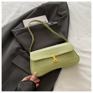 Detail of light green crocodile embossed faux leather underarm bag with gold metal buckle