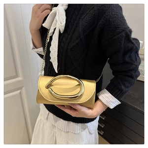 Close-up of champagne gold clutch with chain strap and modern metal buckle detail