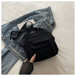 Close-up of black corduroy crossbody bag texture and front flap pocket details