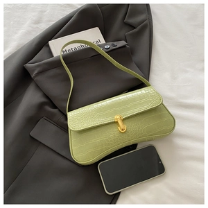 Close-up of avocado green baguette bag with crocodile texture and gold U-shaped metal clasp