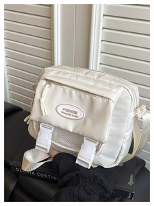 Detail of off-white crossbody bag with front zipper pocket and buckle accents