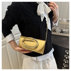Detail view of a vintage gold box clutch with a large oval metal buckle and chain strap