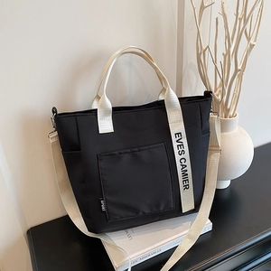 Black canvas tote lunch bag with cream handles and wide shoulder strap for office workers