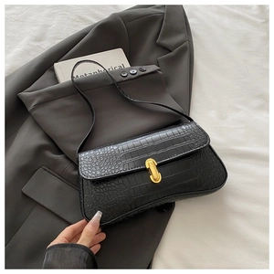 Close-up of black crocodile texture baguette bag with golden metal twist lock detail