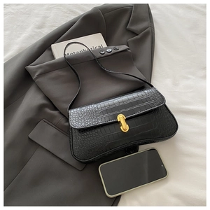 Detail of black crocodile texture baguette bag with a sleek gold oval metal buckle