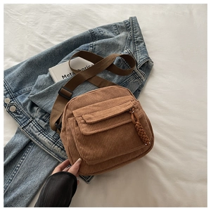 Detailed flat lay of brown corduroy crossbody bag with vertical texture and nylon strap