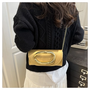 Detail of a mustard satin box bag with a large gold metal buckle on a shoulder chain